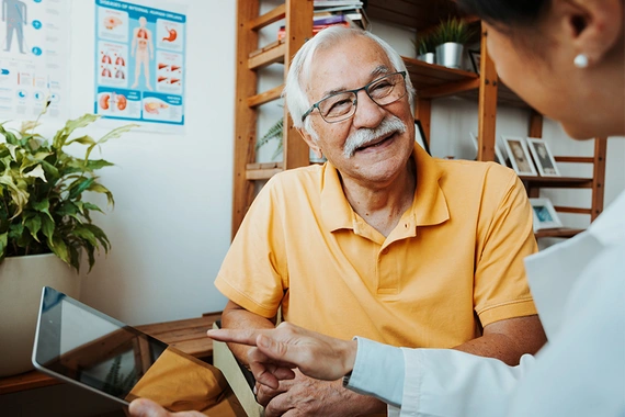 A healthcare professional and senior patient in a conversation using a tablet